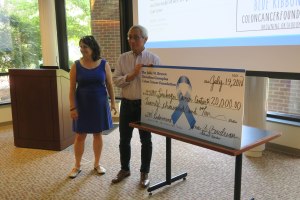 Channing Der and Adrienne Cox stand with the large check from the Julie M. Brown Christina Gianoplus Colon Cancer Foundation.
