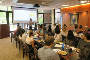 Channing stands in the Pagano Conference room, addressing his lab members.